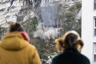 Des curieux regardent des blocs de pierre tomber de la paroi surplombant le quartier de la Barme à Collombey-Muraz (VS).