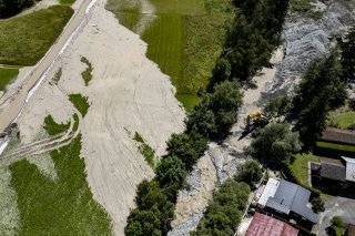 Une vue aérienne montre des ouvriers avec des pelleteuses travaillant sur la coulée de lave torrentielle provenant du torrent du Fregnoley dans le Haut Val de Bagnes