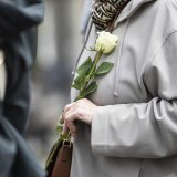 Une personne tient une rose blanche dans sa main lors d'une marche blanche en hommage à la victime après le féminicide d'Epagny le vendredi 18 avril 2025, à Bulle.