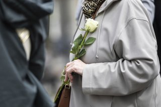 Une personne tient une rose blanche dans sa main lors d'une marche blanche en hommage à la victime après le féminicide d'Epagny le vendredi 18 avril 2025, à Bulle.