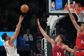 Yanic Konan Niederhäuser (à droite) a dû attendre le "garbage time" pour fouler le parquet des Phoenix Suns de Devin Booker (à gauche, au tir). KEYSTONE/AP/Ross D. Franklin
