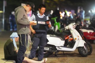 Des passants restent sur place tandis que la police établit un périmètre de sécurité à Bondi Beach après une fusillade signalée à Sydney, dimanche. KEYSTONE/AP/Mark Baker