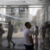 Image d'illustration: des personnes profitent d'un brumisateur géant installé par la ville de Geneve afin de se rafraichir durant la canicule, à Genève, en juillet dernier. KEYSTONE/MARTIAL TREZZINI