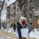 Une femme porte une couverture distribuée par l'agence des Nations Unies pour les réfugiés (HCR) près du site d'une frappe russe sur un immeuble à Kharkiv. KEYSTONE/EPA/SERGEY KOZLOV
