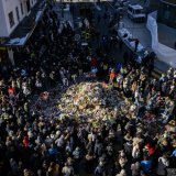 Mourners gather around flowers and candles to commemorate the victims of the fire at the