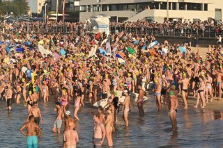 Surfers et nageurs ont rendu hommage aux victimes de l'attentat de Bondi, vendredi, à la plage de Bondi. KEYSTONE/EPA/MICK TSIKAS