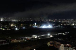 De la fumée s'élève samedi au-dessus de l'aéroport La Carlota à Caracas, suite à un raid aérien américain. KEYSTONE/AP/MATIAS DELACROIX
