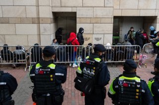 Quelque 70 personnes ont fait la queue jeudi matin pour entrer au tribunal de première instance de West Kowloon, où des dizaines de policiers étaient déployés. KEYSTONE/AP/Chan Long Hei
