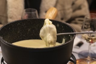 Avant de déguster un bon repas, par exemple une fondue, divers restaurants valaisans offriront à leurs clients un peu de littérature (photo d'illustration). KEYSTONE/LAURENT MERLET