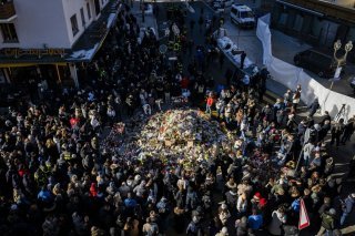 Mourners gather around flowers and candles to commemorate the victims of the fire at the