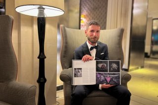 Grégoire Maret présente la double page qui lui est consacrée dans l'album 'Strive for Perfection: The Official Platinum Jubilee Edition'.