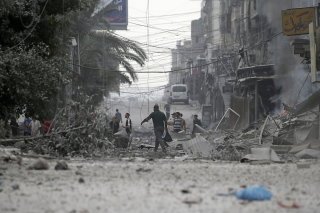 Des Palestiniens marchent dans les ruines à Gaza City. L'attaque israélienne se déroule désormais à huis clos: les communications et internet ont été coupés dans l'enclave palestinienne, selon le gouvernement du Hamas. KEYSTONE/EPA/MOHAMMED SABER