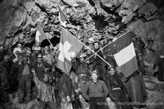 Construction workers celebrate the main breakthrough on April 5, 1962, in the Great St Bernard tunnel. Great St Bernard lies on the north-south axis and connects the city of Martigny in the canton of Valais, Switzerland, with the northern Italian city of Aosta in the eponymous valley. The tunnel measures 5,8 kilometers in length. The works for the first transalpine road tunnel commenced in 1958 and were concluded in March 1964. (KEYSTONE/PHOTOPRESS-ARCHIV/Str) Bauarbeiter feiern am 5. April 1962 den Durchbruch des grossen St. Bernhard-Tunnels. Der grosse Sankt Bernhard verlaeuft in Nord-Sued-Richtung und verbindet die Stadt Martigny im Kanton Wallis mit der oberitalienischen Stadt Aosta im gleichnamigen Tal. Insgesamt hat er eine Laenge von 5,8 km. Die Arbeiten am ersten transalpinen Strassentunnel wurden im Jahr 1958 in Angriff genommen und im Maerz 1964 beendet. (KEYSTONE/PHOTOPRESS-ARCHIV/Str)